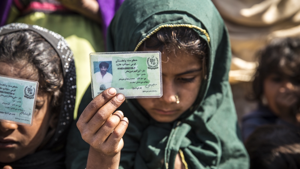 Sundus holds up a national identity card belonging to her father Ibrahim, who was the sole provider for his family of seven [Faras Ghani/Al Jazeera]