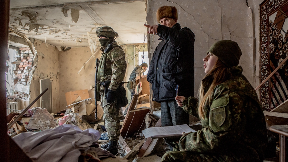 Anatoliy Karabaz, 70, right, shows the destruction of the apartment to police inspector [Anton Skyba/Al Jazeera]