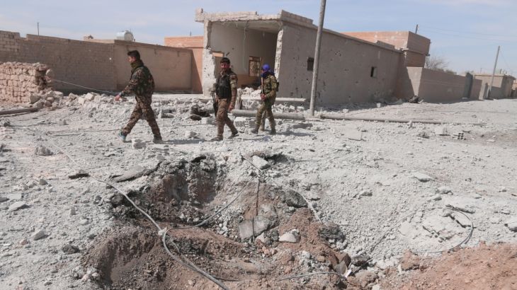 Syrian Democratic Forces (SDF) fighters walk near damaged ground east of Raqqa city