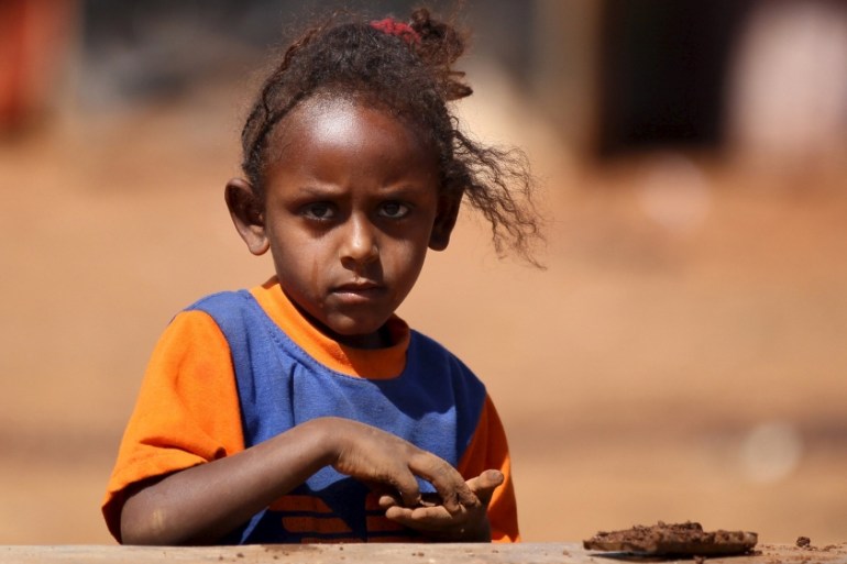 An Eritrean refugee girl plays with clay in front of their shelter in Mai-Aini refugee camp near the Eritrean boarder in the Tigrai region in Ethiopia