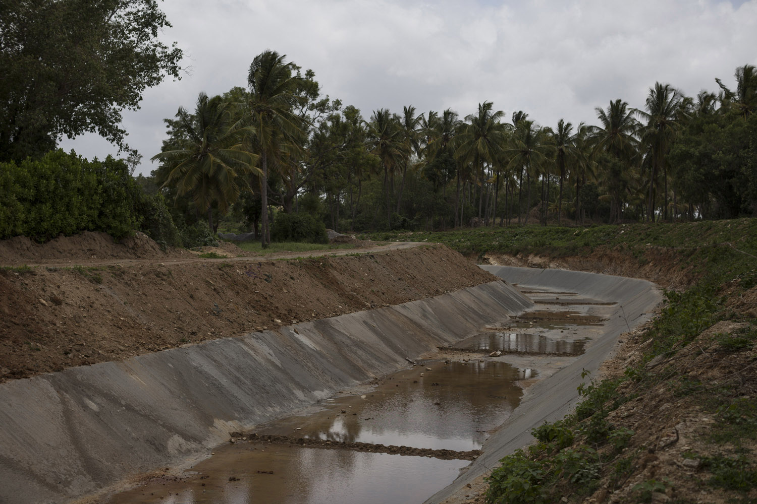 An irrigation channel from the Krishna Raja Sagara dam runs dry on a hot day in the middle of the rainy season in July 2016. Mandya district is supposed to be irrigated by the dam but as the monsoon becomes unreliable and the rains diminish every year, there simply isn't enough water for all the farmed areas [Janos Chiala/Al Jazeera]