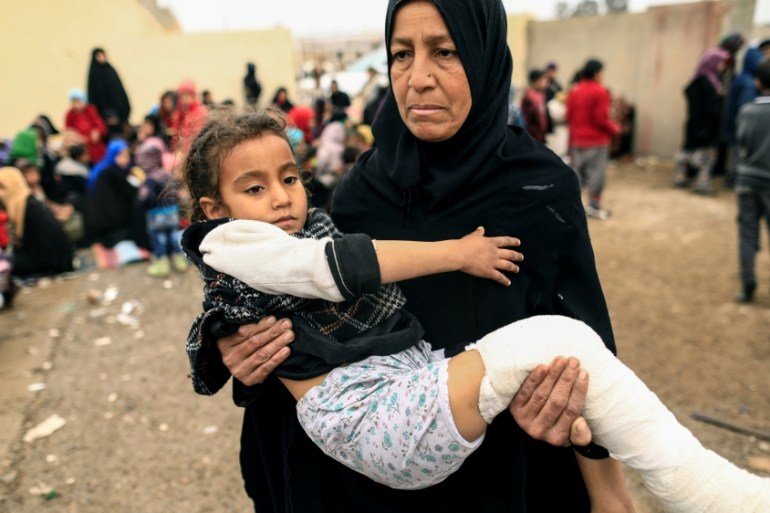 A displaced Iraqi woman who just fled her home carries her injured daughter at a screening center, as Iraqi forces battle with Islamic State militants, in western Mosul
