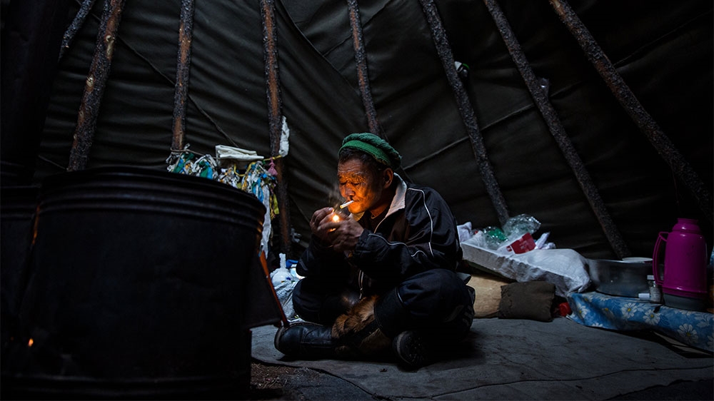 Delger Gorshik, seated in his teepee, says the Dukha are now restricted in where they can go to let their reindeer graze [Taylor Weidman/Al Jazeera]