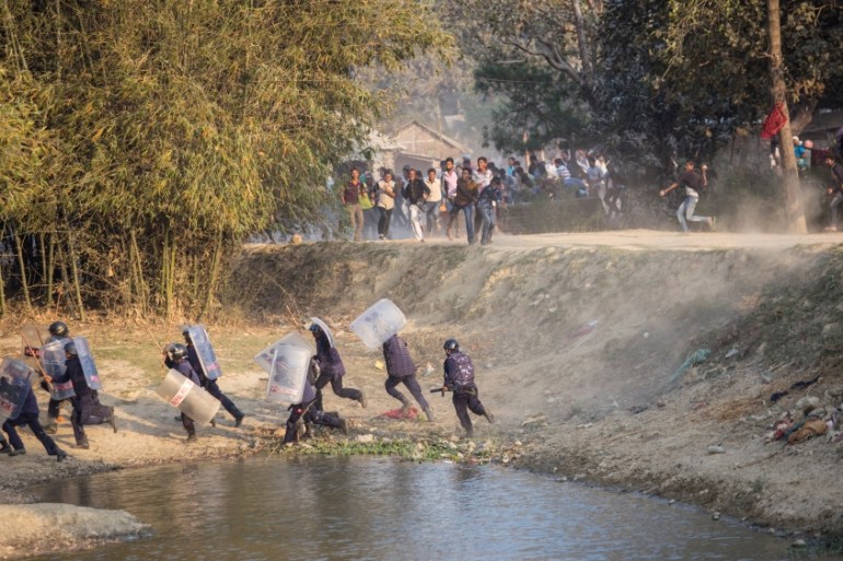 Nepalese riot police run for cover as Madhesi activists hurl stones at them in Saptari District, Nepal