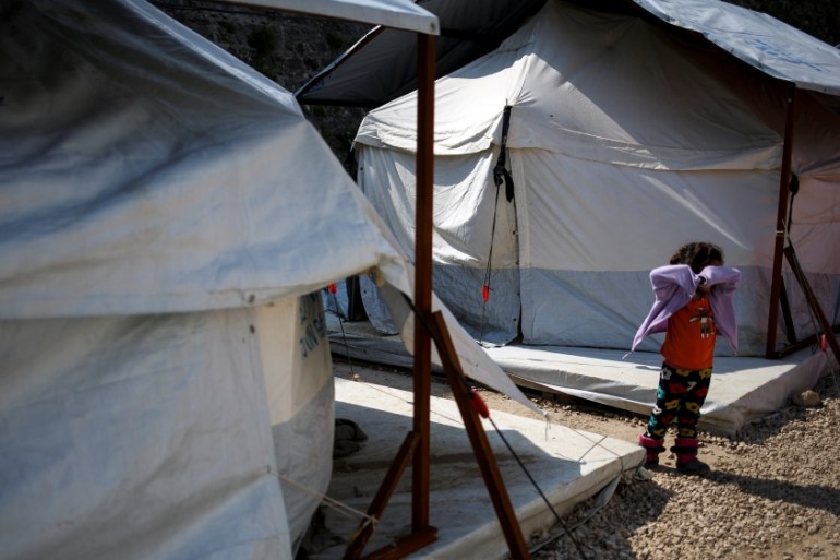 A girl stands among tents at the Souda municipality-run camp for refugees and migrants on the island of Chios
