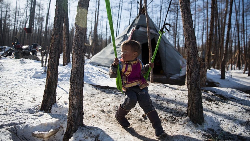 A young Dukha boy plays in front of his family's teepee near Tsagaannuur, Mongolia, on March 7. [Taylor Weidman/Al Jazeera]