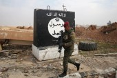 An Iraqi soldier walks next to a wall painted with the black flag commonly used by ISIL, near Arabi neighbourhood, north of Mosul, Iraq, January 21 [Khalid al Mousily/Reuters]