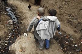 Boys walk down an alley at a slum on the outskirts of Islamabad