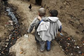 Boys walk down an alley at a slum on the outskirts of Islamabad