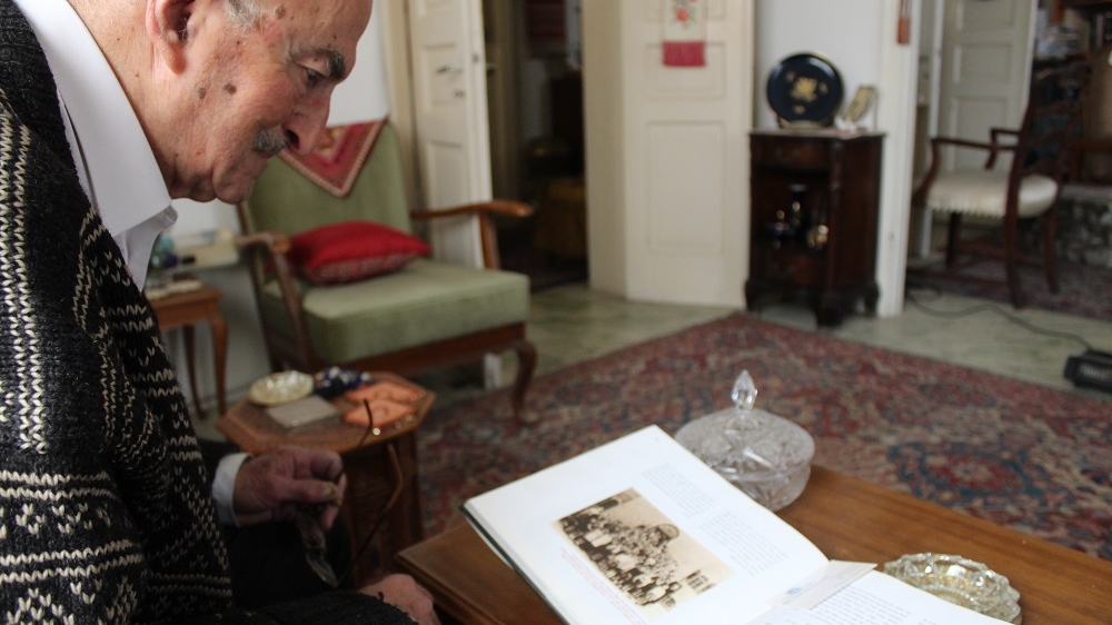 Teddy looks at photographs of his 1938-1939 class in the German Colony, which was near his home neighbourhoods of Talbiyeh and Katamon. [Mary Pelletier/Al Jazeera]