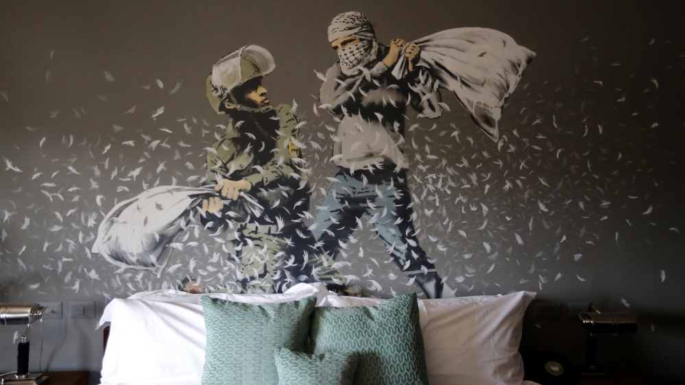  A wall painting in the Walled Off Hotel portrays a 'pillow fight' between an Israeli soldier and a Palestinian youth [Abed Al Hashlamoun/EPA]