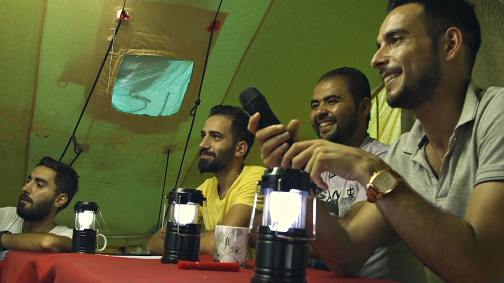 Sameer, Mahmoud, Basil and Mustafa, the four friends behind refugees.tv, sit behind the Refugees Got Talent judges' table in the Oreokastro refugee camp, Greece [Al Jazeera]