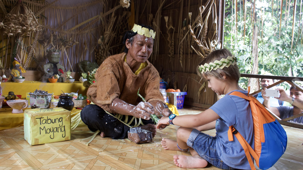 The shaman dabs a visiting boy’s hand with chalk as a blessing for Hair Moyang [Kate Mayberry/Al Jazeera]