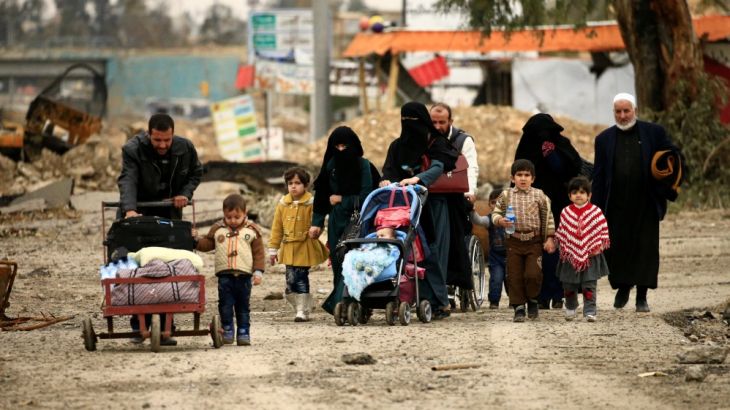 Displaced Iraqi families who fled from clashes during a battle between Iraqi forces and Islamic State militants walk with their children in Mosul