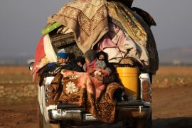 People ride a vehicle stacked with their belongings after fleeing clashes in the northern Syrian town of al-Bab