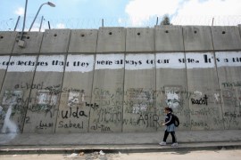 A Palestinian girl walks past part of an open letter, painted on the controversial Israeli barrier in al-Ram in the West Bank on the outskirts of Jerusalem