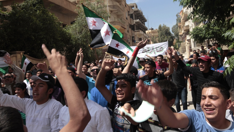 Demonstrators chant slogans and wave Syrian opposition flags during a protest against President Bashar al-Assad in Raqqa province, east Syria, May 17, 2013 [Hamid Khatib/Reuters]