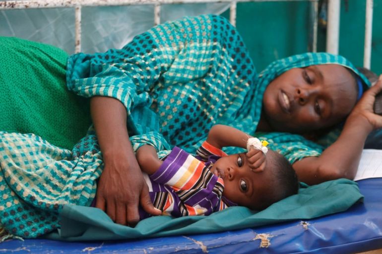 An internally displaced Somali woman holds her child receiving treatment inside a ward dedicated for diarrhoea patients at Banadir hospital in Somalia''s capital Mogadishu