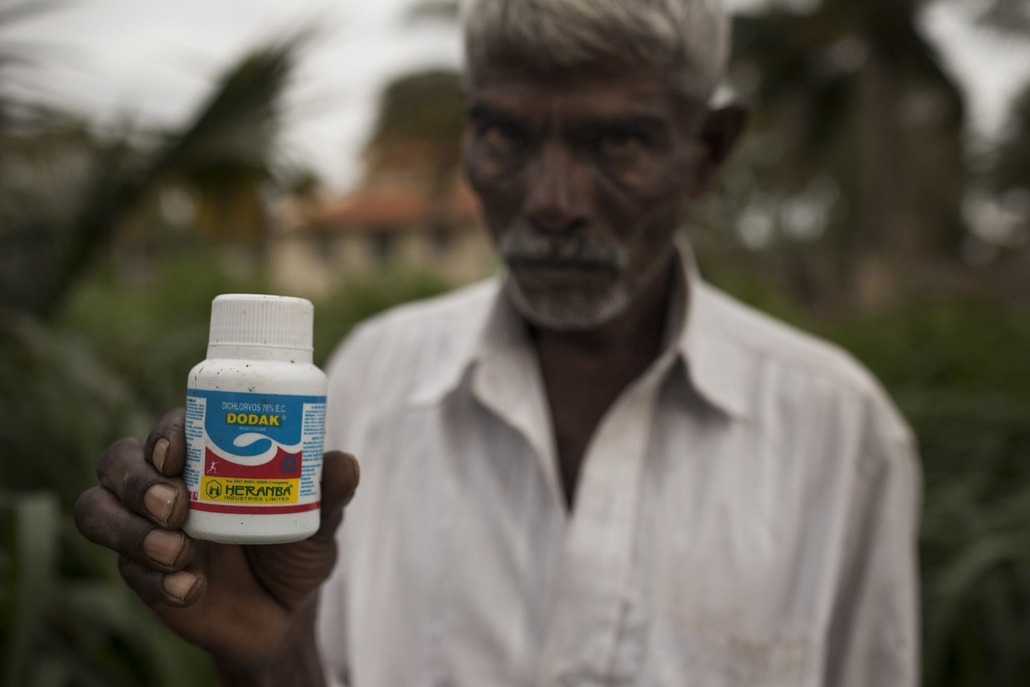 Shivalinga Gowda, 50, holds a bottle of insecticide like the one his 23-year-old son Madhu consumed to kill himself after accumulating large debts while managing the family farm in the village of Arechakanahalli [Janos Chiala/Al Jazeera]