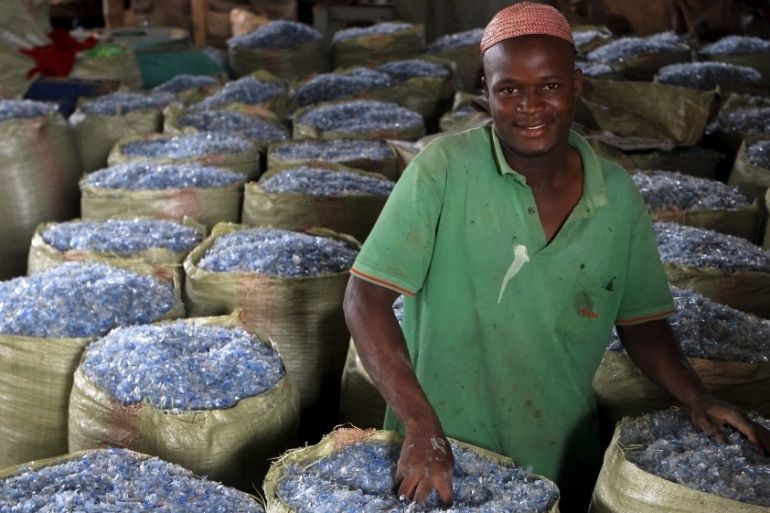 An employee of a recycling plant fills up sacks with plastics pellets ready for export to China at their factory at a dumping site on the outskirts of Kampala