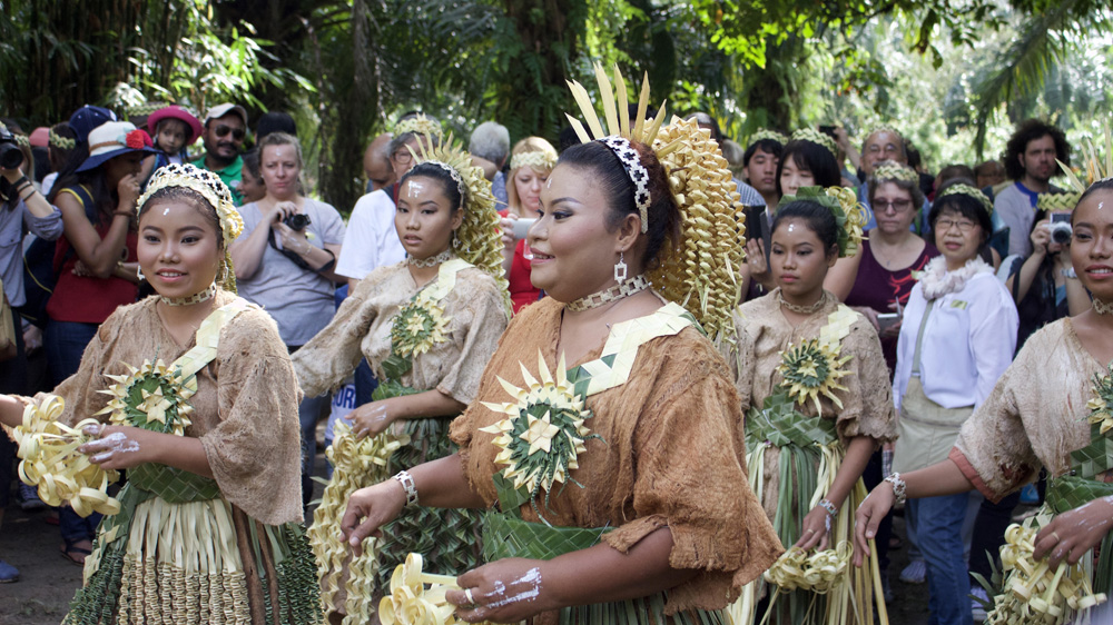 Mah Meri women celebrate Hari Moyang - a day to honour the spirits - as tourists look on [Kate Mayberry/Al Jazeera]