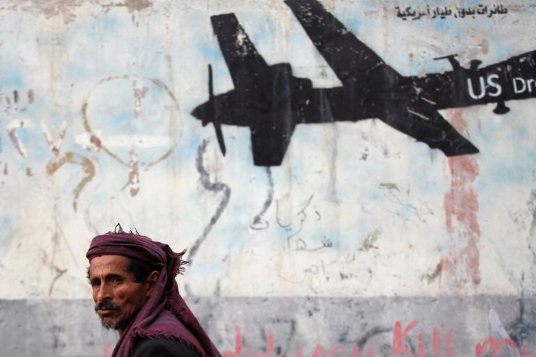 Man walks past a graffiti, denouncing strikes by U.S. drones in Yemen, painted on a wall in Sanaa, Yemen