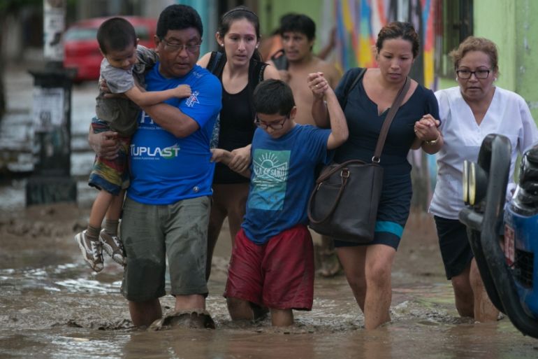 Residents cross a flooded street in Trujillo after deadly floods in Peru