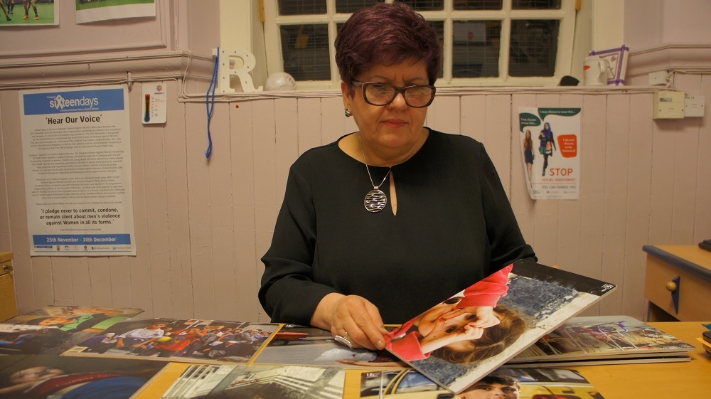 Director of the Maryhill Integration Network, Remzije Sherifi, looks through photos from Syria, which were used for an exhibition in the Scottish borders [Zab Mustefa/Al Jazeera]