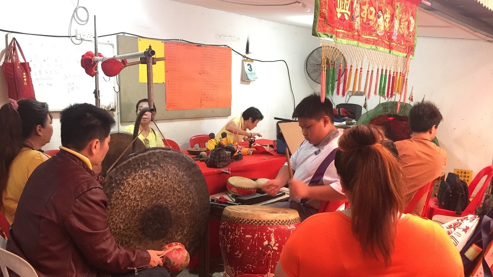 Tina Quek's son plays the drum  at a Qing Chang performance. [Amandas Ong/Al Jazeera]