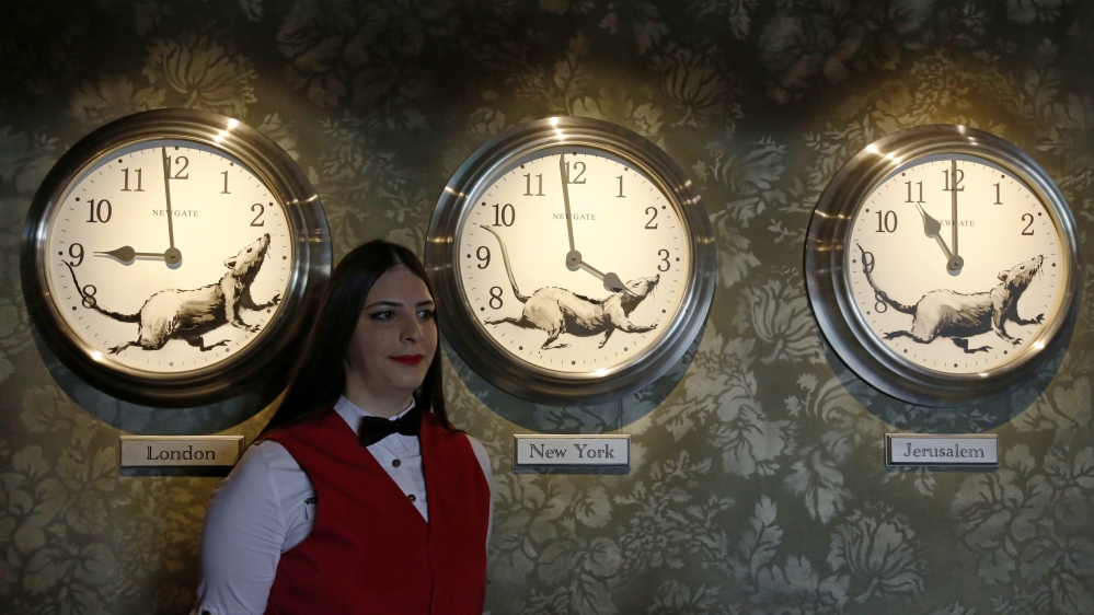 An employee poses in front of the 'three rat clocks' at Banksy's Walled Off Hotel in Bethlehem [Abed Al Hashlamoun/EPA]