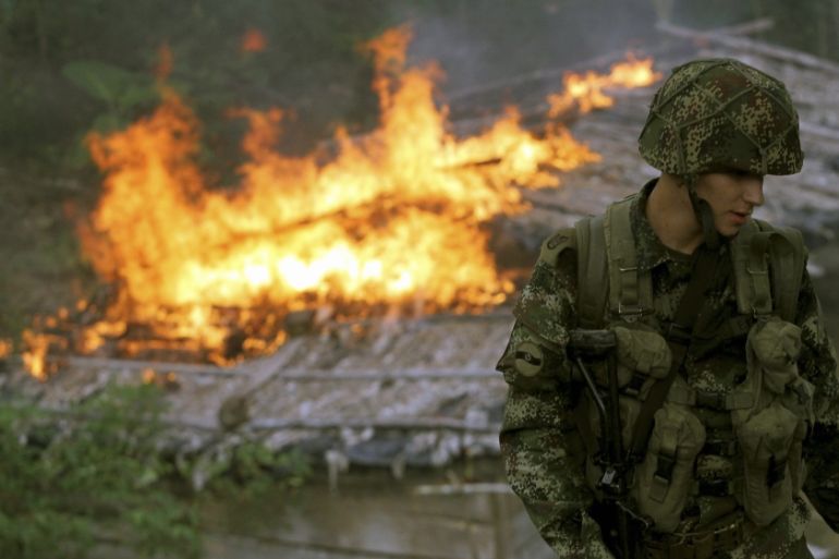 A soldier from the Seventh Division of the Colombian National Army looks on in front of a shack after members of the unit burn it down during an operation at a plantation in Yali