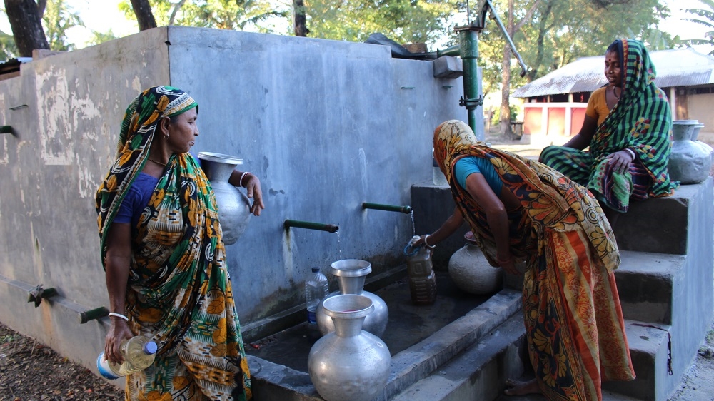 Women gather around the water pump in Fultala. In the rainy season, the line at the pump is shorter as women collect rainwater in plastic drums and pots.  [Neha Thirani Bagri/The GroundTruth Project]