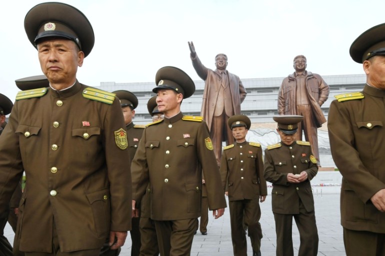 North Korean soldiers walk in front of bronze statues of North Korea''s late founder Kim Il-sung and late leader Kim Jong Il at Mansudae in Pyongyang