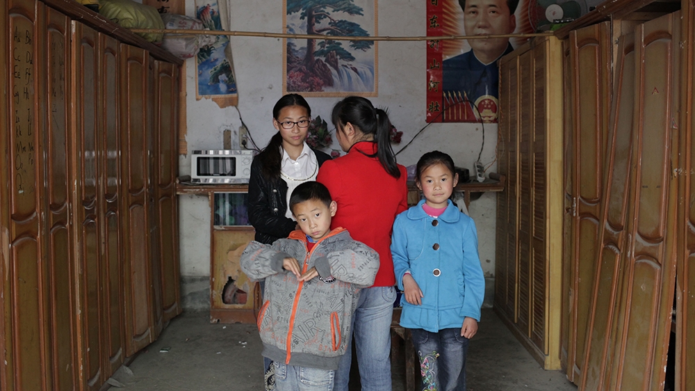 Chen Kaijing with her three children. So far, Chen hasn't managed to find her biological parents [Han Meng/Al Jazeera]
