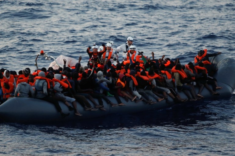 Rescuers of MOAS hand out life jackets to migrants on board a rubber dinghy in the central Mediterranean north of Sabratha on the Libyan coast