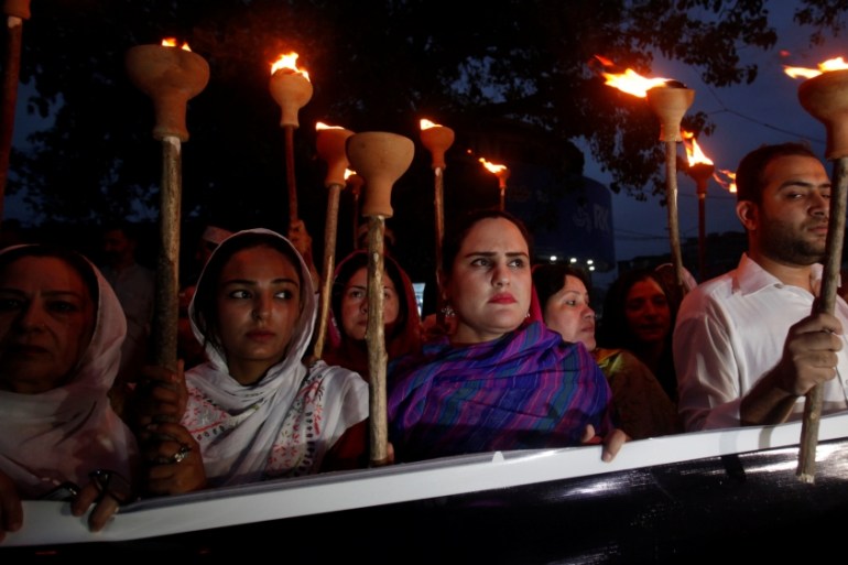 Protesters hold lamps during a protest in Peshawar