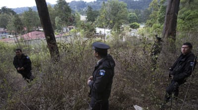 On March 15, police stand guard in the pine forest which surrounds the Virgen de la Asuncion shelter. Girls who escaped from the shelter the day before the fire remain missing [AP/Moises Castillo]