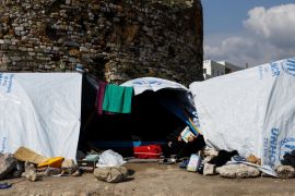 A migrant reads a book outside his tent at the Souda municipality-run camp for refugees and migrants on the island of Chios