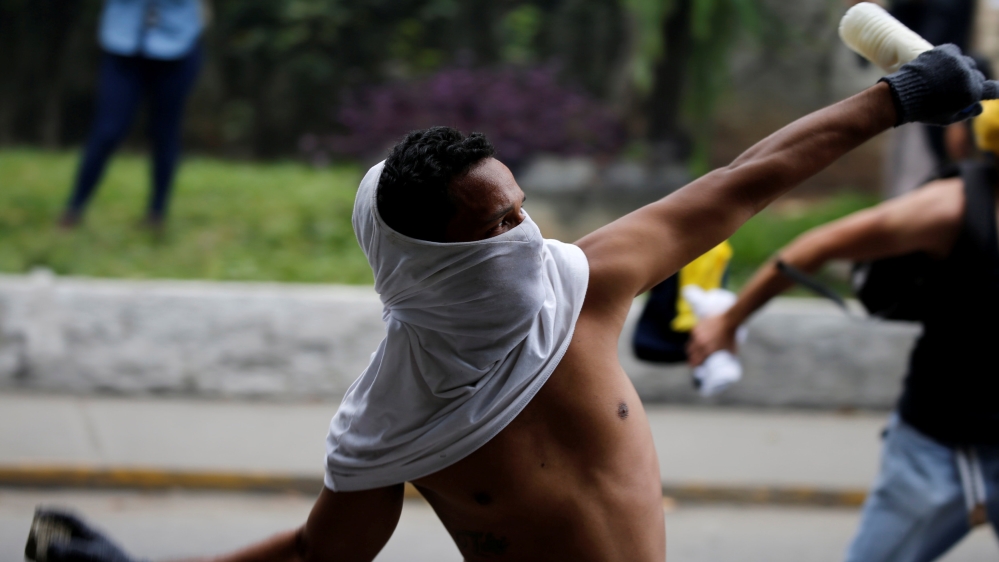 A demonstrator clashes with riot police in Caracas [Carlos Garcia Rawlins/Reuters]