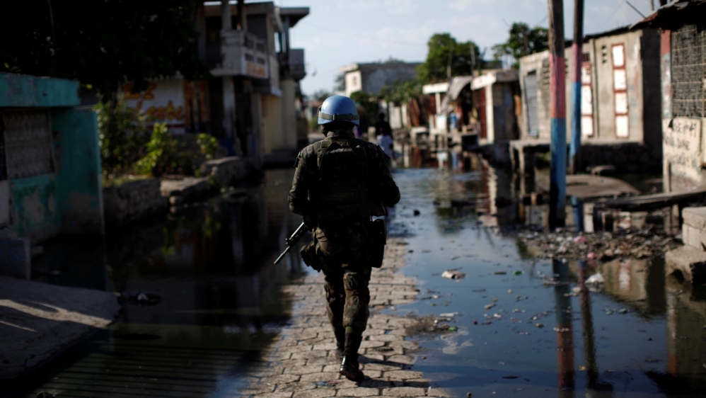 A UN peacekeeper in a flooded street during a patrol with Haitian national police officers and members of United Nations Police in Cite Soleil, Port-au-Prince, Haiti on March 3, 2017 [Andres Martinez Casares/Reuters]