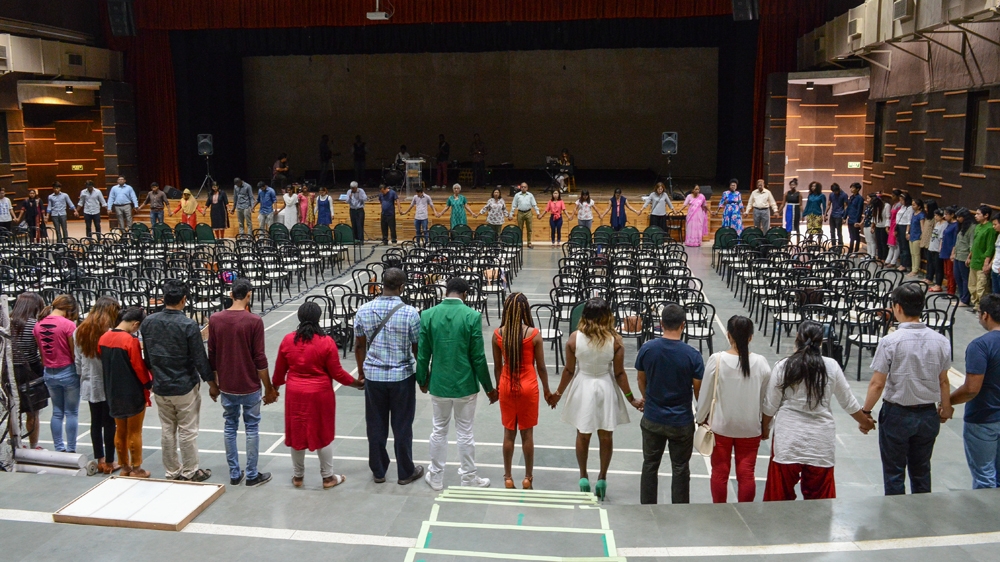 At a church service held in a Greater Noida private school's auditorium, congregants form a circle and pray for the safety of their 'African brothers'. [Maya Prabhu/Al Jazeera]