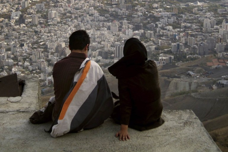File photo of an Iranian couple sitting, overlooking the city of Tehran
