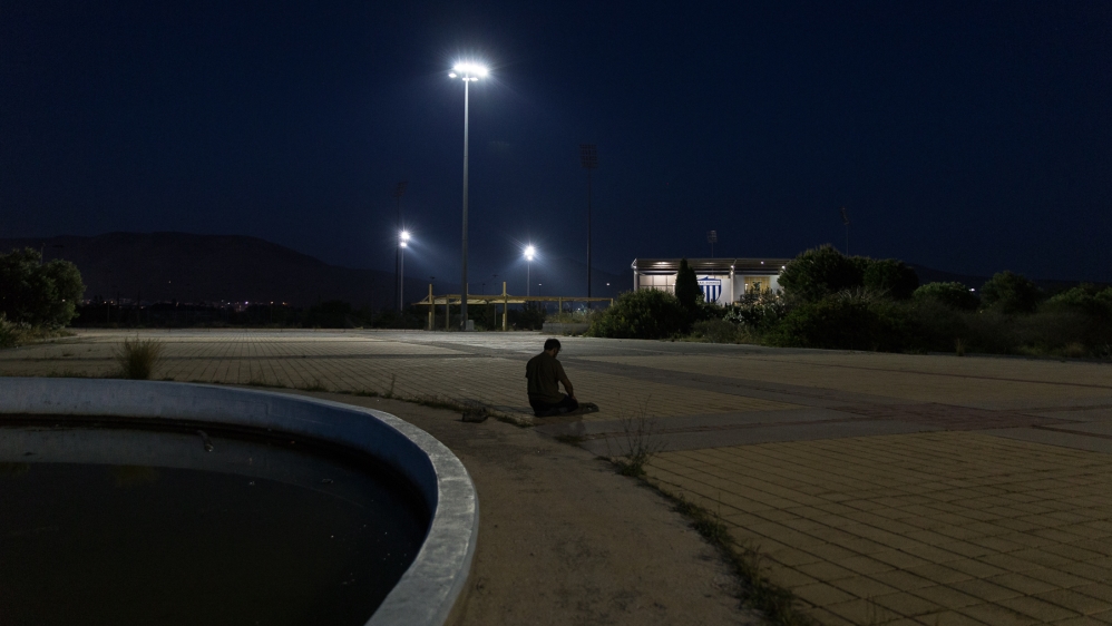 Qahar prays near a water fountain at the Elliniko refugee camp outside the Greek capital [Kelly Lynn Lunde/Al Jazeera]