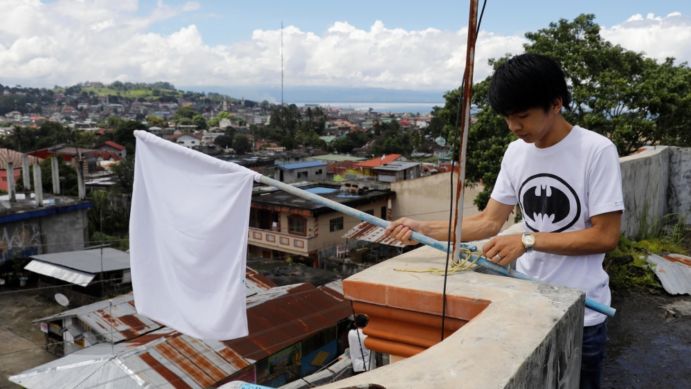 A resident displays a white flag on rooftop of a house in Marawi City [Erik De Castro/Reuters]