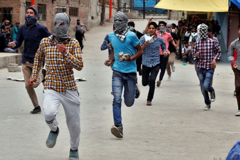 Protesters run as they prepare to hurl stones towards the Indian police during a protest after Friday prayers, in Srinagar