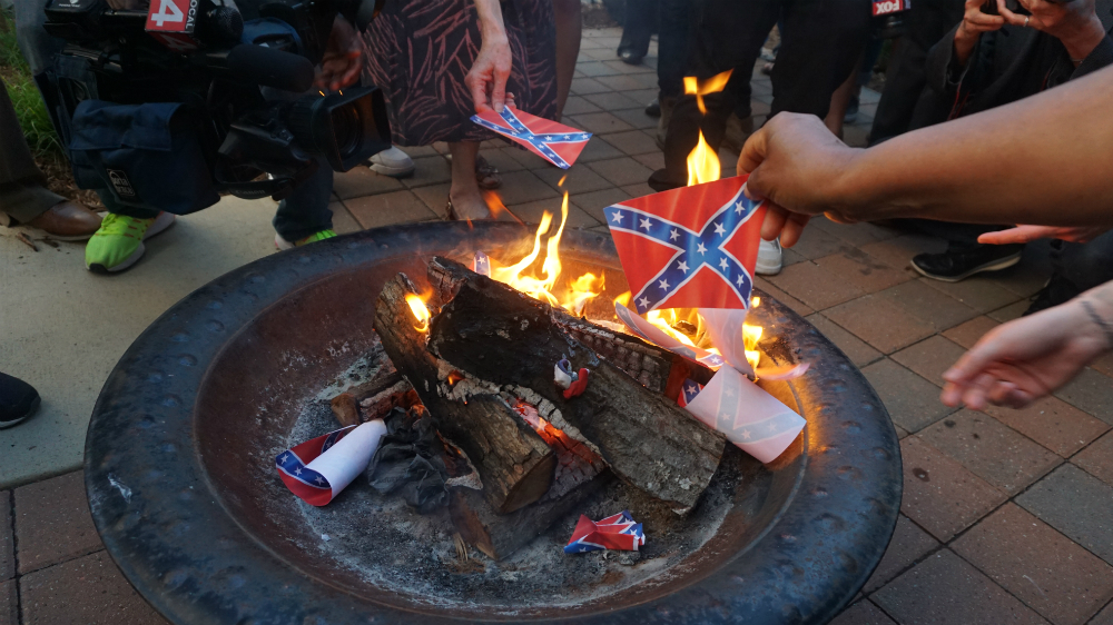 After a Confederate flag burning held at the N’Namdi Center for Contemporary Art in Detroit on Memorial Day, audience members placed their own paper flags in the fire [Kurt Nagl/Al Jazeera] 