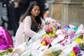 A woman places flowers on an impromptu memorial at Manchester Town Hall for the victims of an attack at Manchester Arena, Manchester