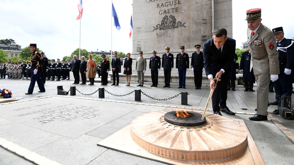  Macron lights the flame during a ceremony at the Tomb of the Unknown Soldier at the Arc de Triomphe in Paris [Alain Jocard/Reuters]