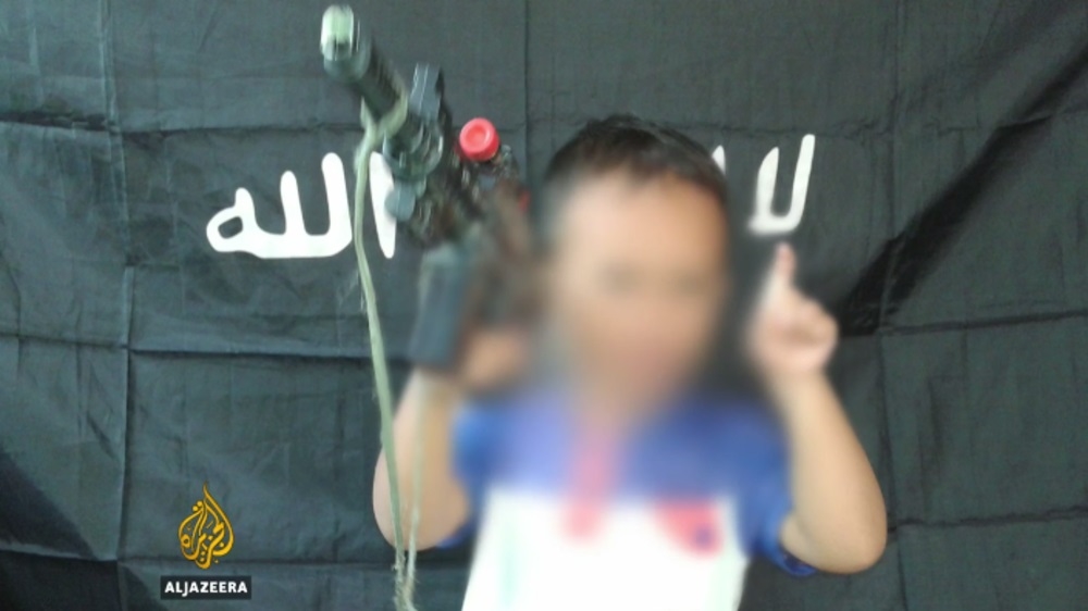  In this image, a child stands in front of a black ISIL flag [Al Jazeera]
