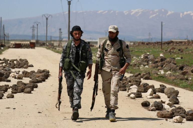 Free Syrian Army fighters carry their weapons as they walk in the northern province of Quneitra